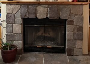 A stone fireplace with wood mantle