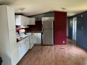 A small kitchen with a red wall and a stainless fridge
