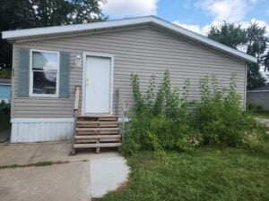 Heavy weeds around a doublewide mobile home