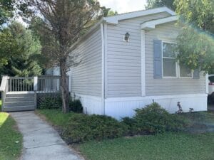 A singlewide mobile home with a large tree near it