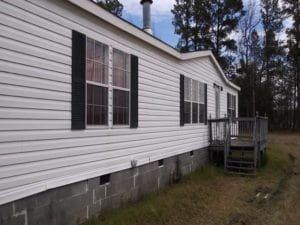 A doublewide mobile home with gray siding and black shutters