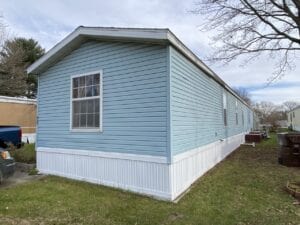 A blue mobile home with white skirting