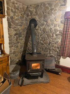 A corner wood stove with a stone back drop