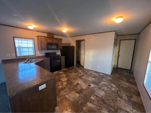 A remodeled kitchen in a mobile home with dark floor and cupboards