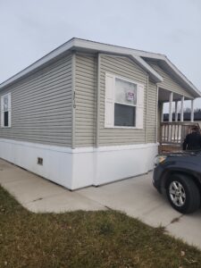 A large new doublewide mobile manufactured home with tan siding