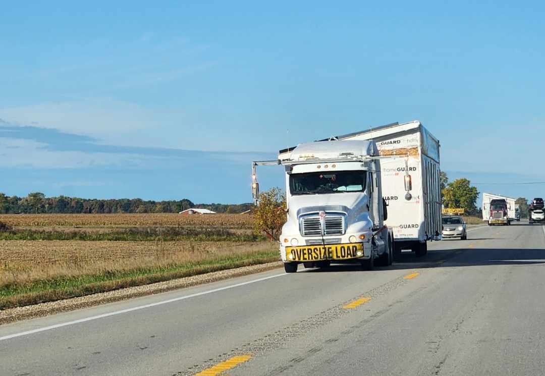 A white toter truck hauling part of a doublewide down the road