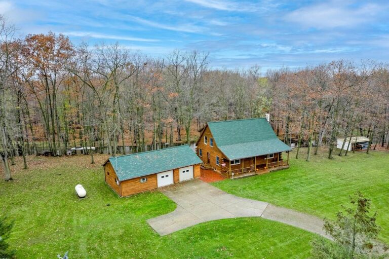 A log home with an attached garage with a large green grass lawn