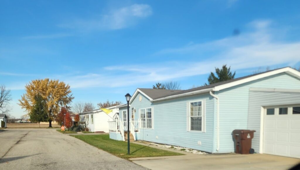 A blue doublewide with a tree in the background