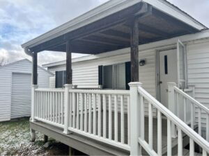 A doublewide mobile home with a large front covered deck
