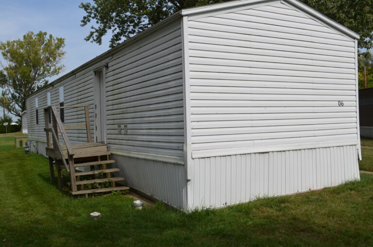 The backside of a white singlewide with vinyl siding