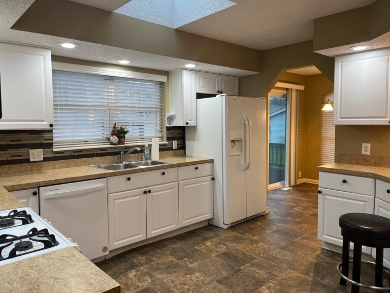 A large kitchen in a mobile home with white cupboards