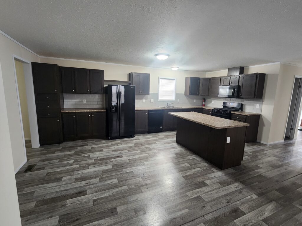 A large kitchen in a mobile home with dark wood cabinets