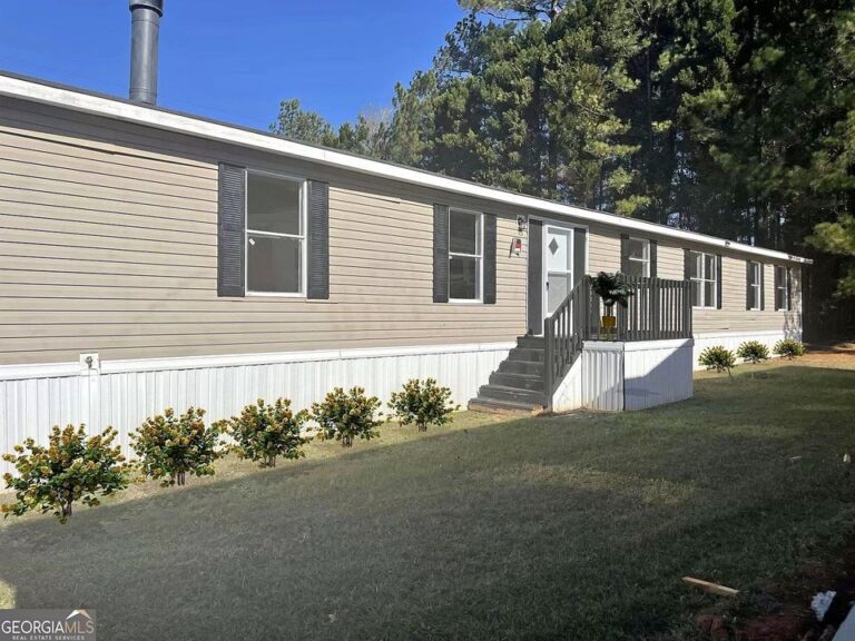 A mobile home with new landscaping and a nice deck