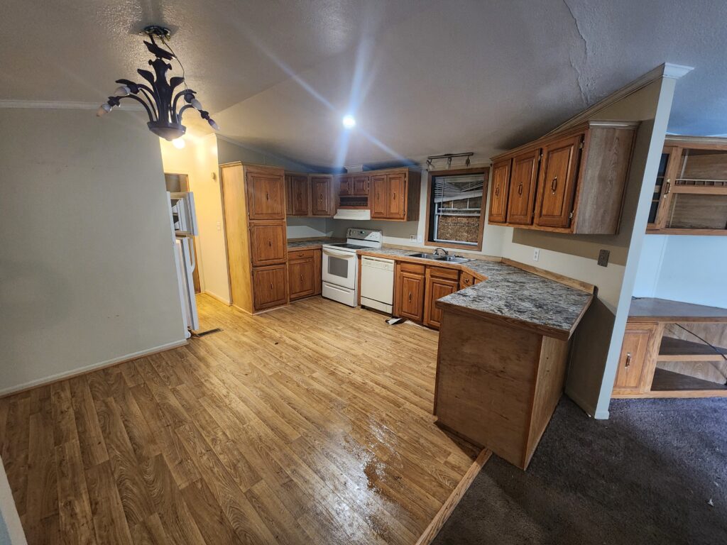 A kitchen in a triple wide manufactured home with wood floors