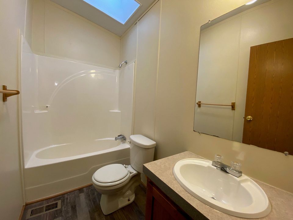A cream colored wall in a bathroom with dark brown floors