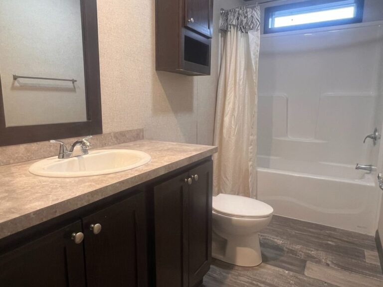 A bathroom with cream colored walls and a white toilet and shower