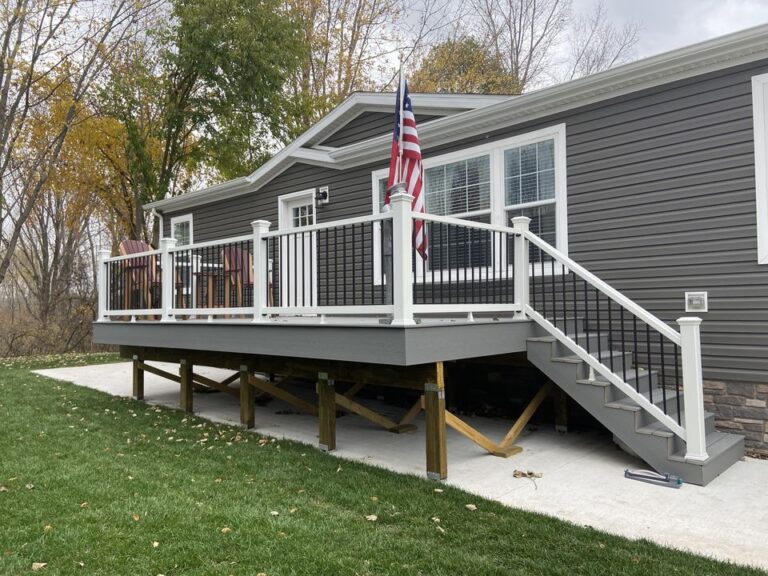 A dark gray mobile manufactured home with a large deck for sale