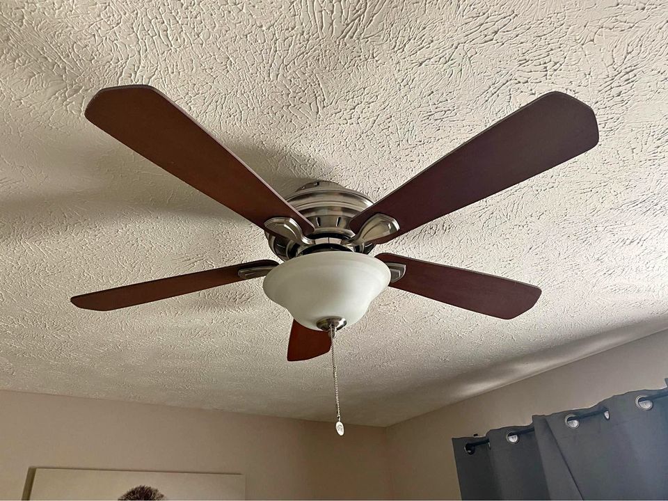 A ceiling fan with the lights off on a ceiling