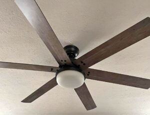 A ceiling fan on the ceiling with dark blades