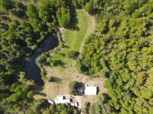 An aerial view of a mobile home on a wooded lot