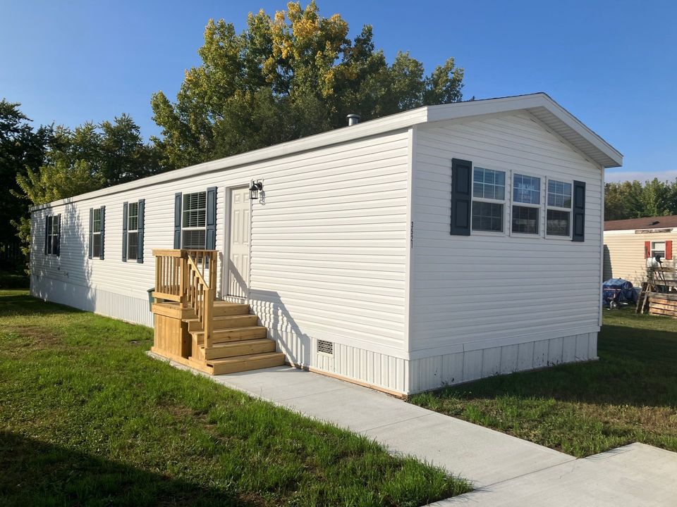 A white singlewide mobile home with a new wood deck