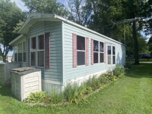 A tiny mobile home with blue siding and red shutters