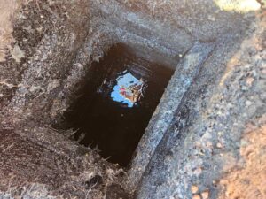 A hole in the ground leading down to the septic tank area