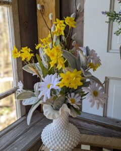 A vase with yellow and white flowers in it