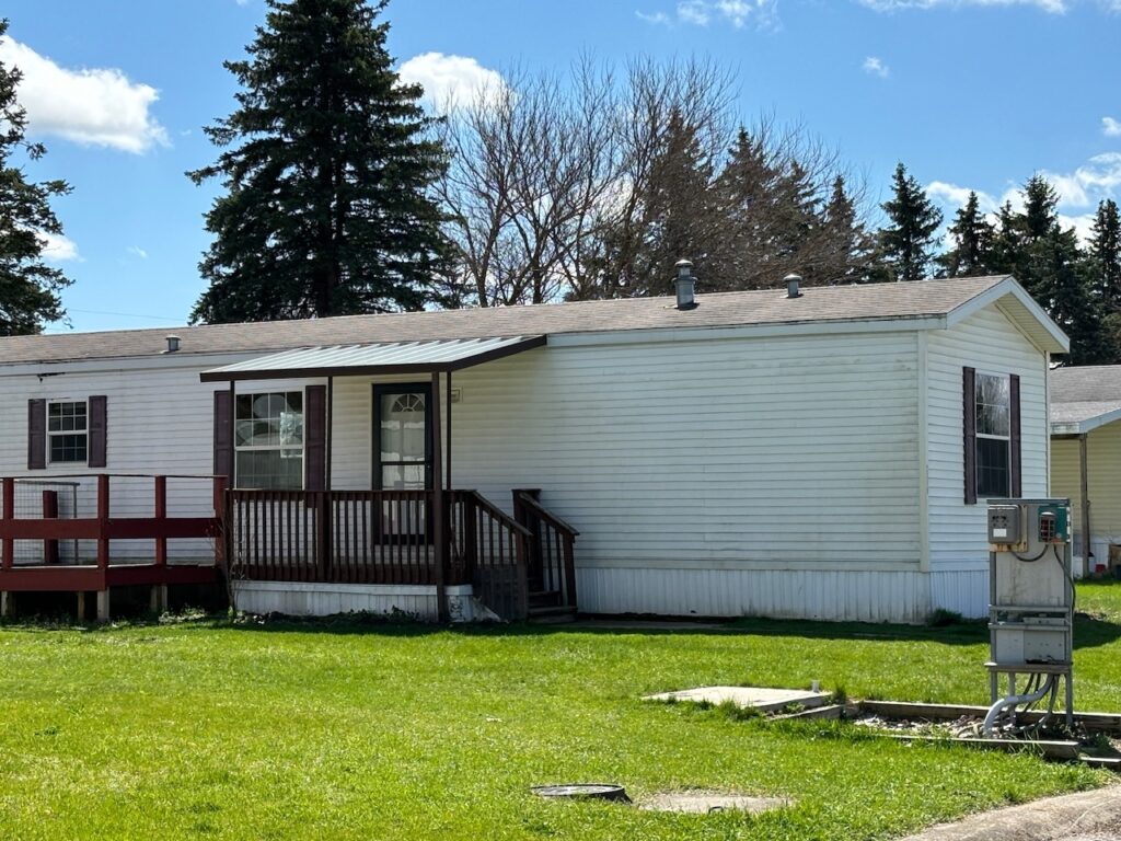 A white singlewide mobile home with covered porch