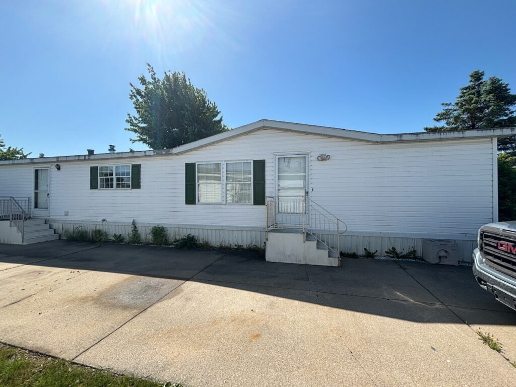 A white doublewide mobile home on a cement slab