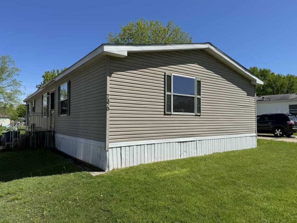 A brown doublewide mobile home with dark brown shutters