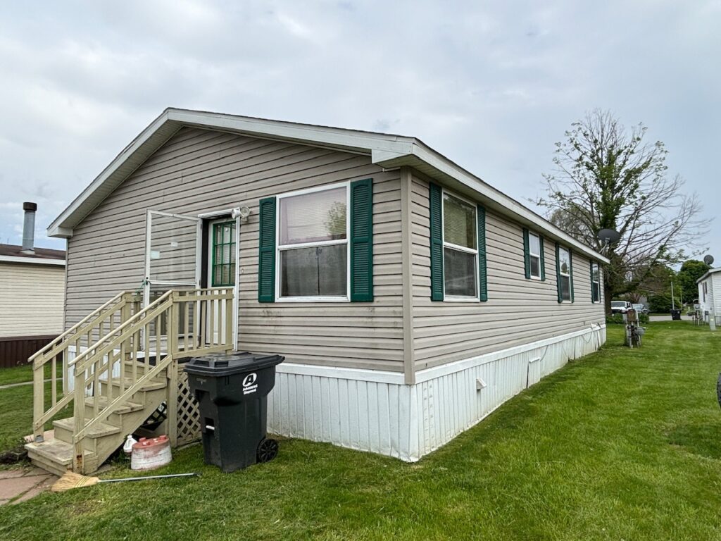 A tan colored doublewide with green shutters