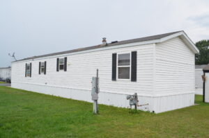 A white singlewide mobile home in a park