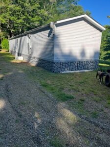 A singlewide mobile home with rock skirting