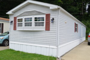 A gray singlewide with burgundy shutters