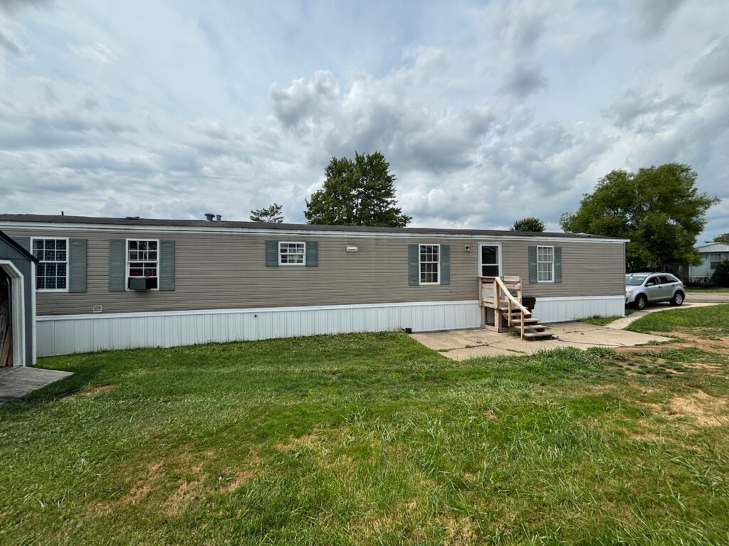 A singlewide brown mobile home on land