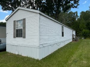 A white singlewide mobile home with vinyl siding