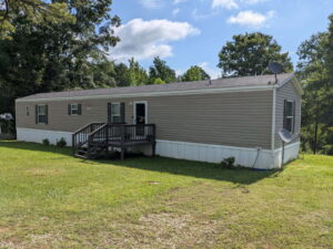 Double wide mobile home on private land in Missouri with deck and landscaping
