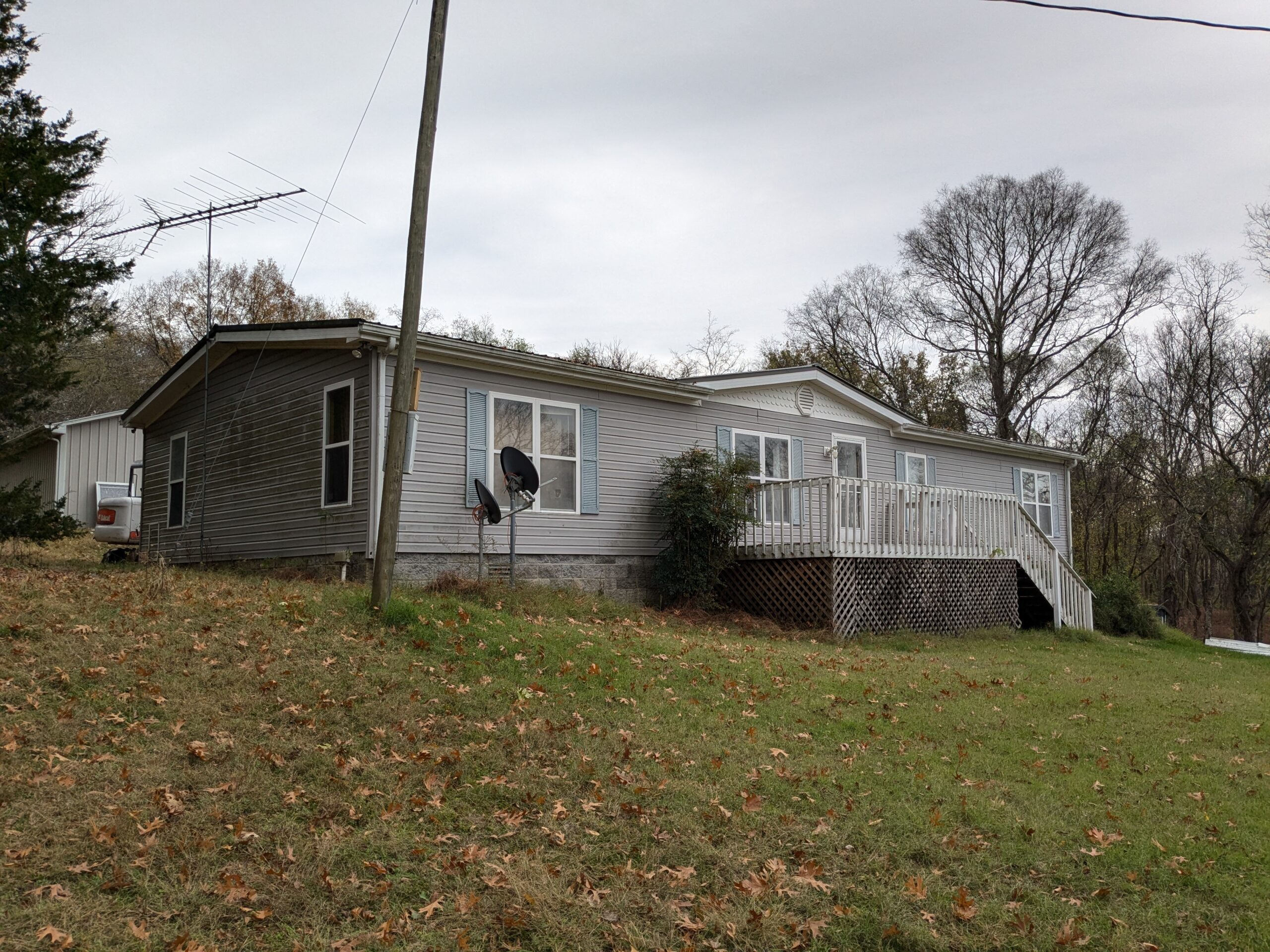 Sell Mobile Home Fast Cash - Private Land Michigan Gray mobile home on private land with deck sold for cash by experienced mobile home buyers in Michigan