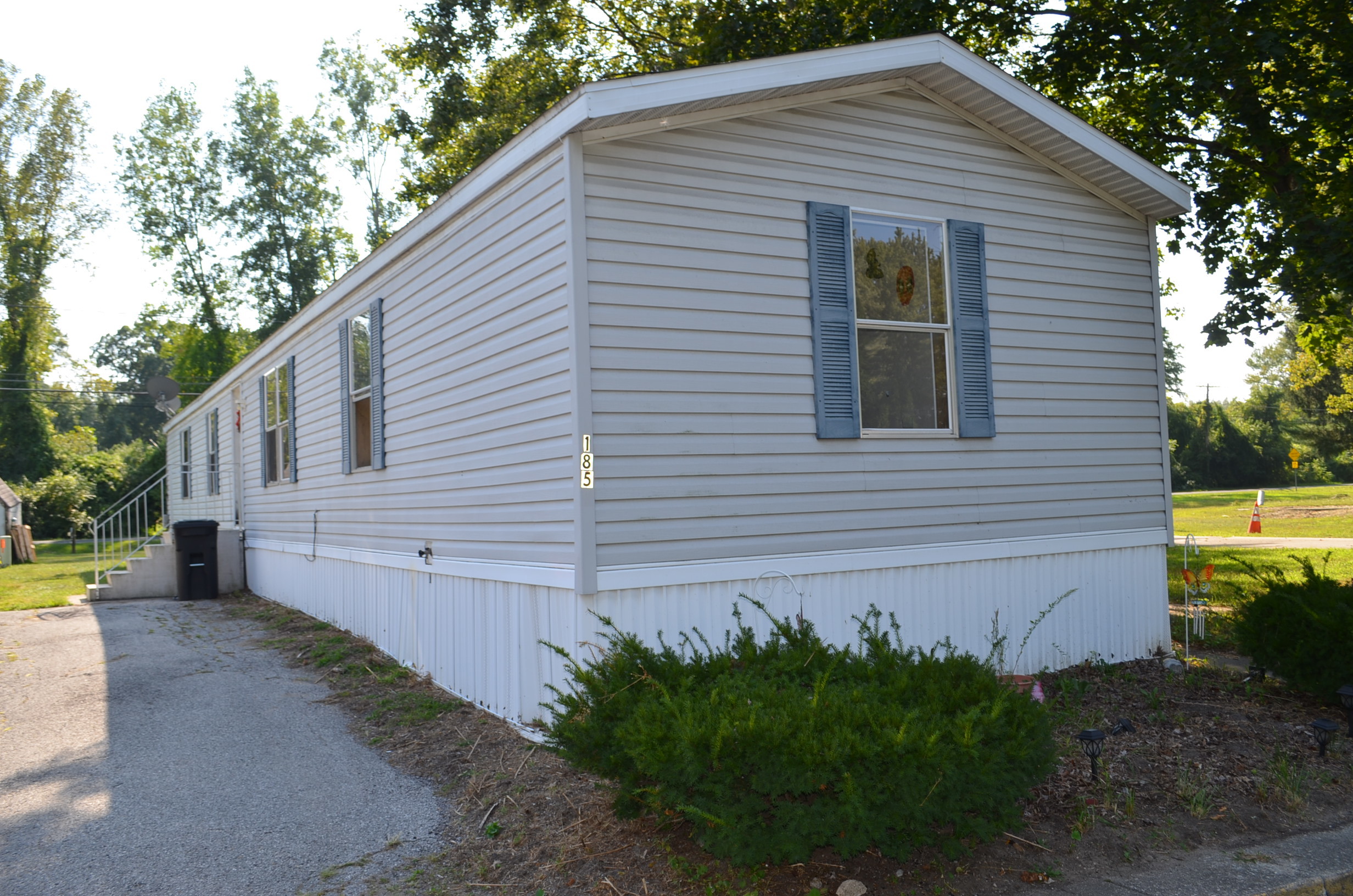 Mobile Home Cash Sale - Any Condition Welcome White mobile home with blue shutters purchased for cash by professional mobile home buyers
